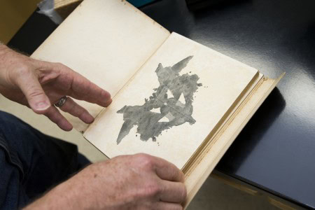 Psychology and environmental studies professor Rick Barnes opens an original printing of a set of Rorschach inkblots from the 1920's.