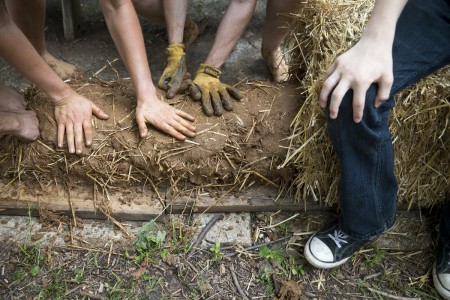 Students practice packing fresh cob to form a wall that could be used in a sustainable structure.