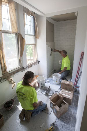 Workers tile one of the single-stall bathrooms.