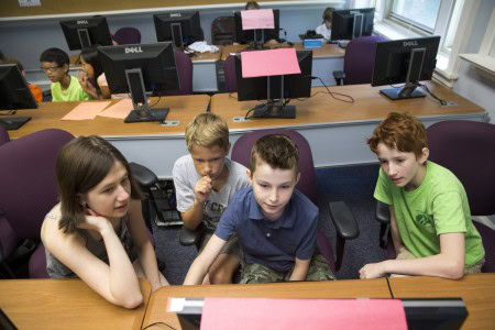 Participants in the TC3 Kids Coding camp gather around a computer.