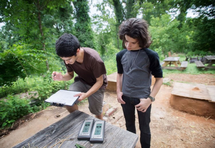 Hagay Haut (left) of Randolph College and E.C. Glass student Spencer Cohen take readings on temperature and humidity for the tiny houses they built on campus. (Photo by Jill Nance)