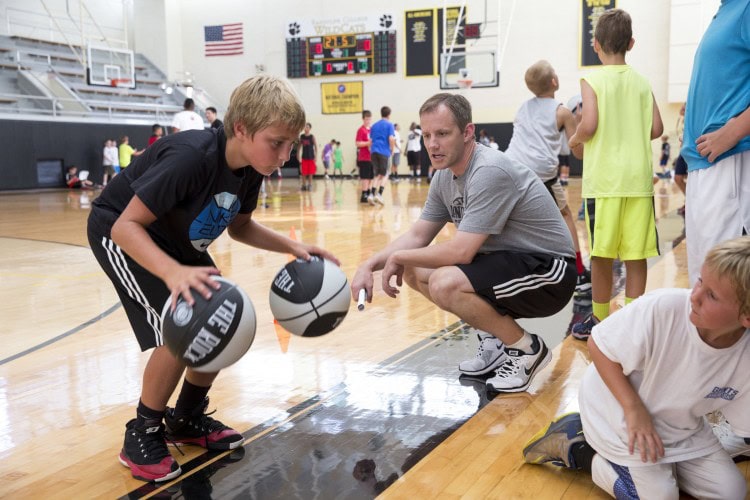 Head men's basketball coach and camp director Clay Nunley talks a camper through a dribbling exercise.