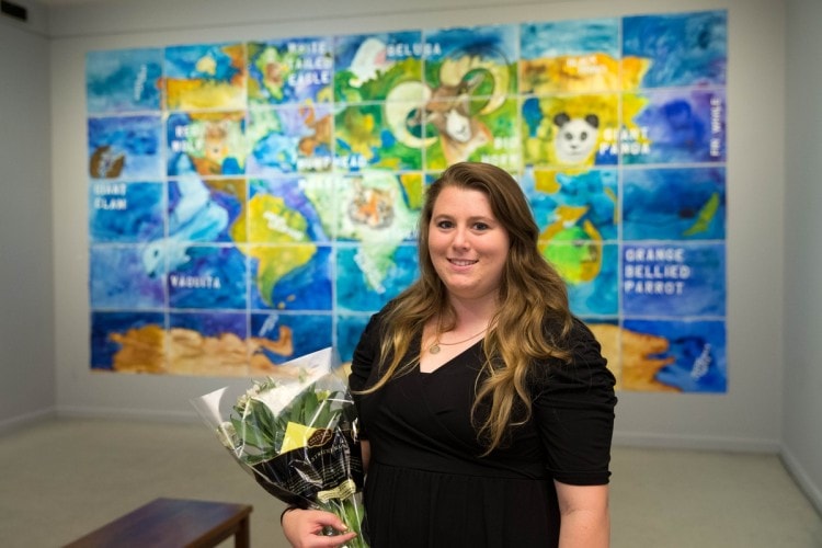 Andrea Mewhinney '16 stands in front of her artwork.