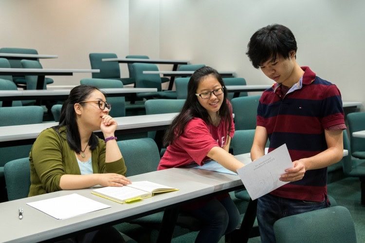 Mathematics professor Jia Wan observes as Mengjin Sun '19 and Nhut Dang '18 study an equation.