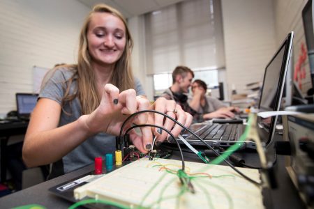 A physics student configures a device that tracks sound levels as part of a Summer Research project.