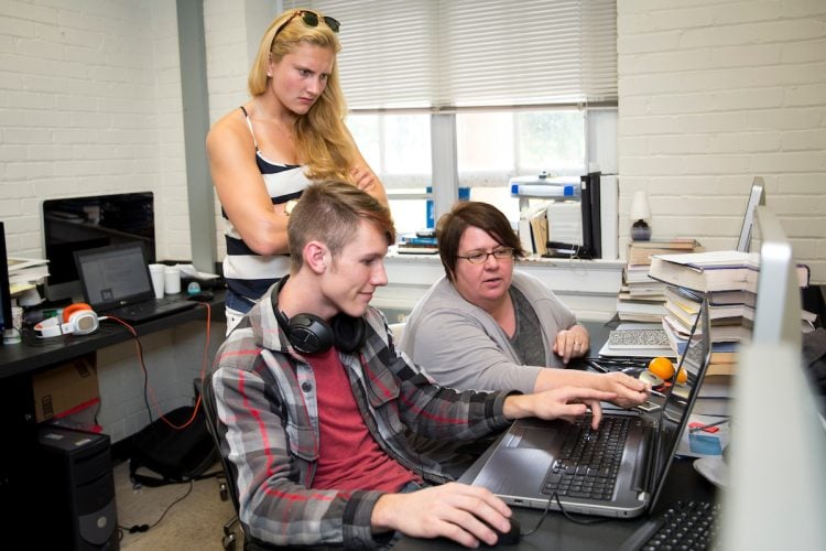 Students work with physics professor.