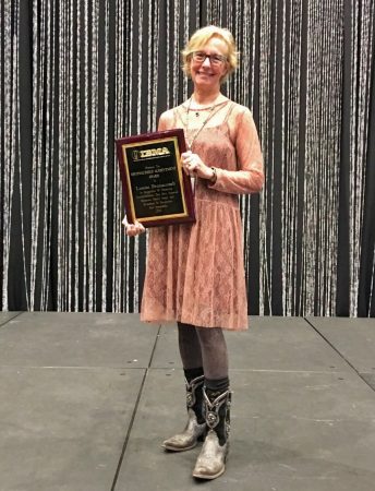 Louisa Branscomb '71 holding her 2017 Distinguished Achievement Award from the International Bluegrass Music Association.