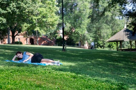 Student laying on the grass, studying on front campus