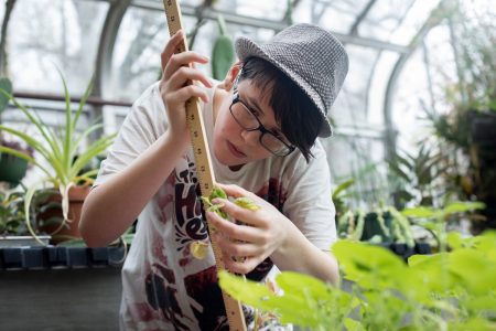 A student takes measurements for a plant in the greenhouse behind Martin Science Building