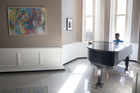 A student plays piano in Main Hall lobby