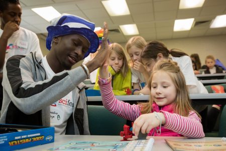 Amadou Beye '19 high fives a young girl at Randolph College's Science Festival