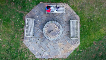 An aerial view, looking straight down at the Sundial and a student sitting on a nearby bench