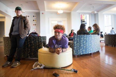 A male student and other students sitting in the Hampson Commons