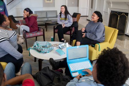 Students, sitting in a circle, hanging out in Main Hall lobby