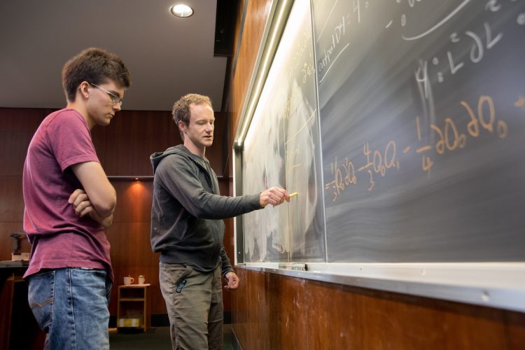 Jude Quintero '20 (left) and mathematics professor Michael Penn work on an equation