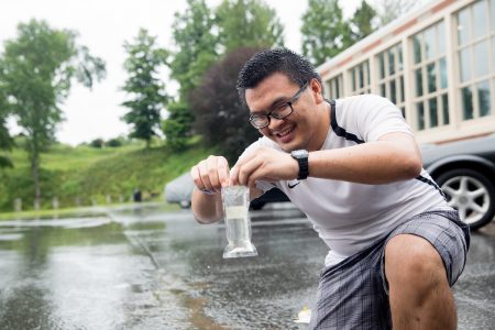 Thinh Bill Pham '20 collects a sample of rainwater from a parking lot on campus