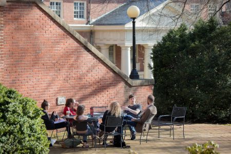 Students and their professor sit around a table outside 