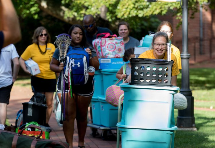 Move-in volunteers and new students push luggage carts along the Red Brick Path Move-in volunteers and new students push luggage carts along the Red Brick Path