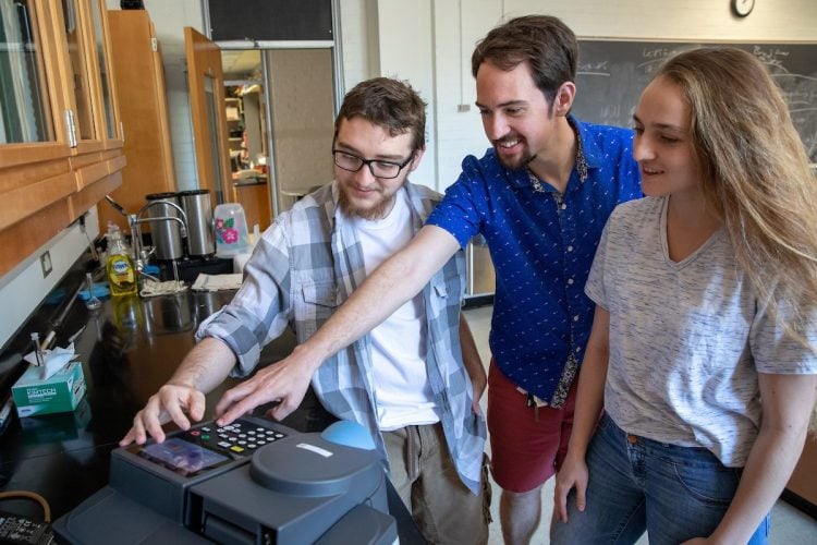 (From left) Matthew Williams, professor Jesse Kern, and Leo Galopin experiment with lab testing equipment