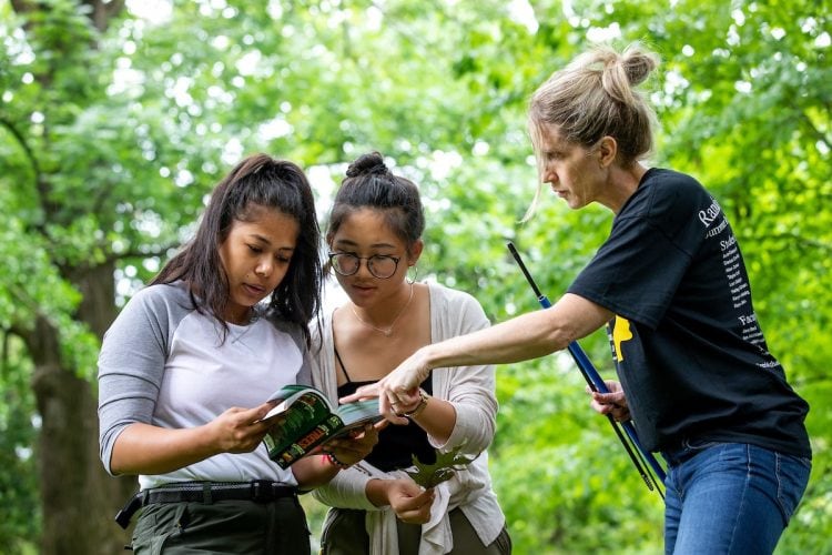 (from left) Ranjitkar, Jin, and Warren consult a field guide during one of their forest inventories