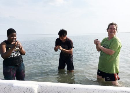 (From left) Jdody Misidor, Alex Kulvivat, and professor Sarah Sojka collect sediment samples from the water