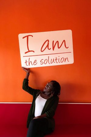 Ranita Opoku-Sarfo with a sign that reads "I am the solution"