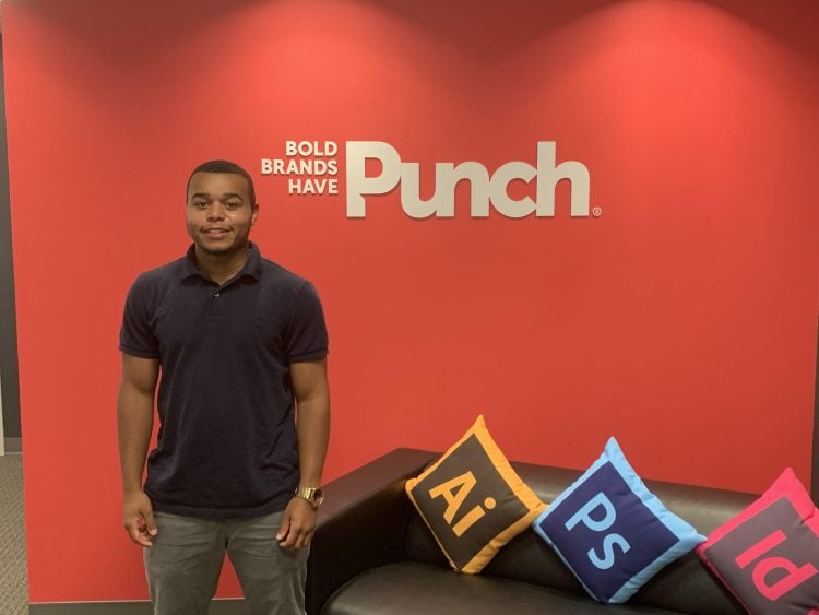 Jared Ruddock in front of red wall with Punch logo on it