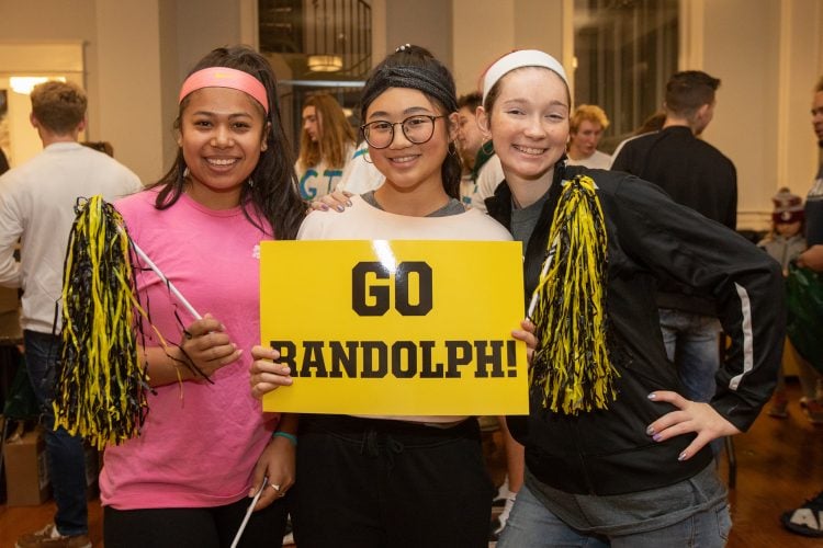 Three students pose with a sign that reads "Go Randolph"