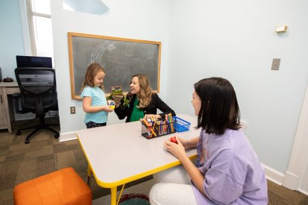 Psychology professor Sara Beck and her daughter work with Cassidy Carter in the new children's research space