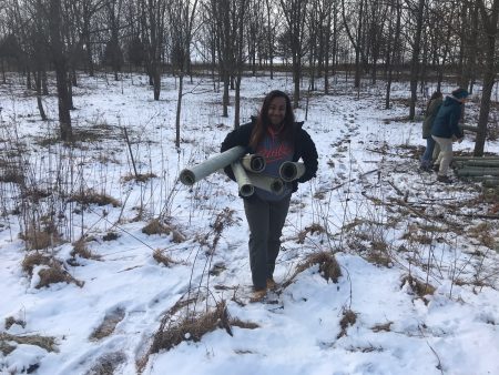 Tyrah Cobb-Davis helping load used tree shelters for future reforestation projects.