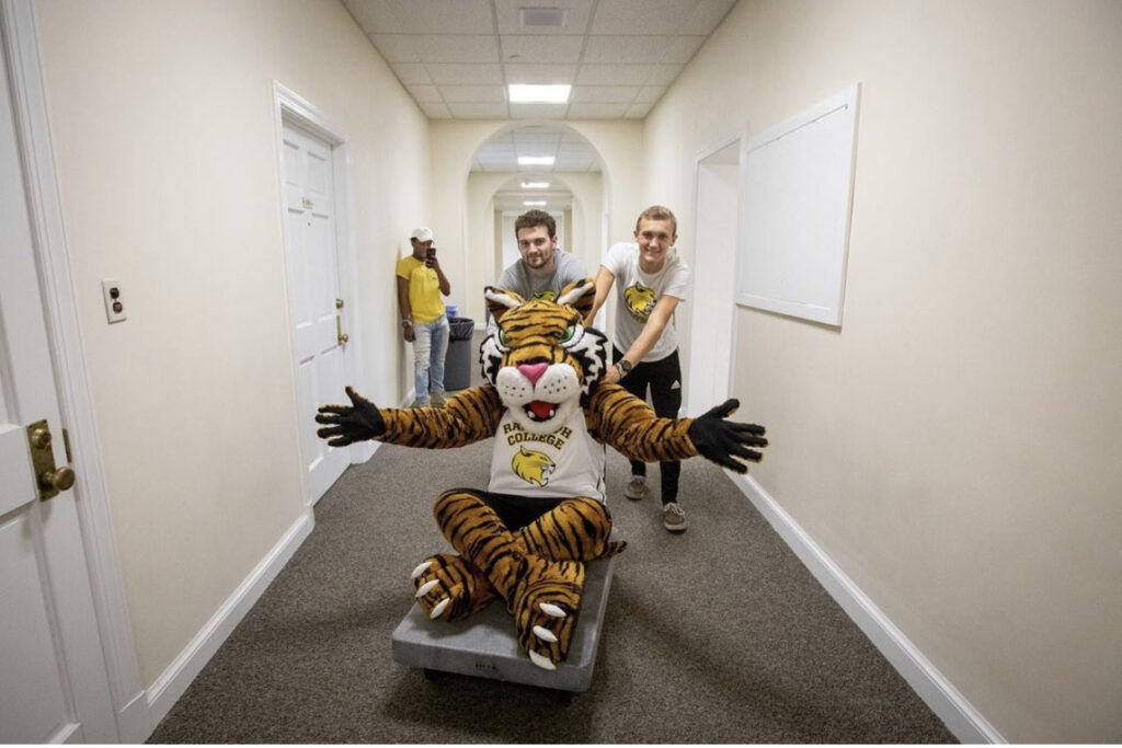 student push Wanda Wildcat on a furniture cart on move in day