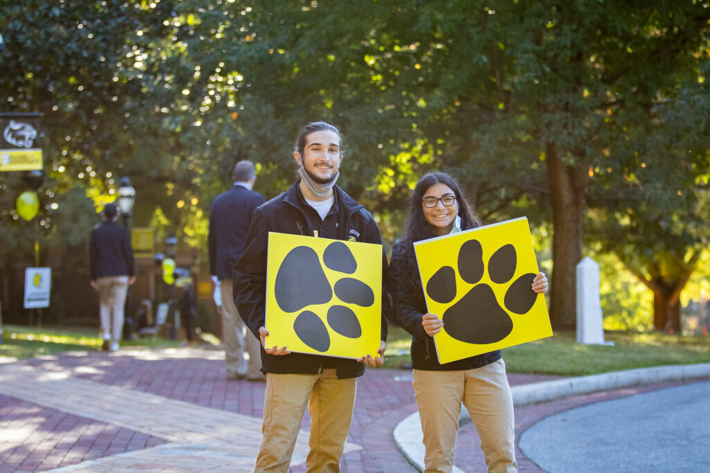 William and Zu hold up signs showing Wanda Wildcat's footprints