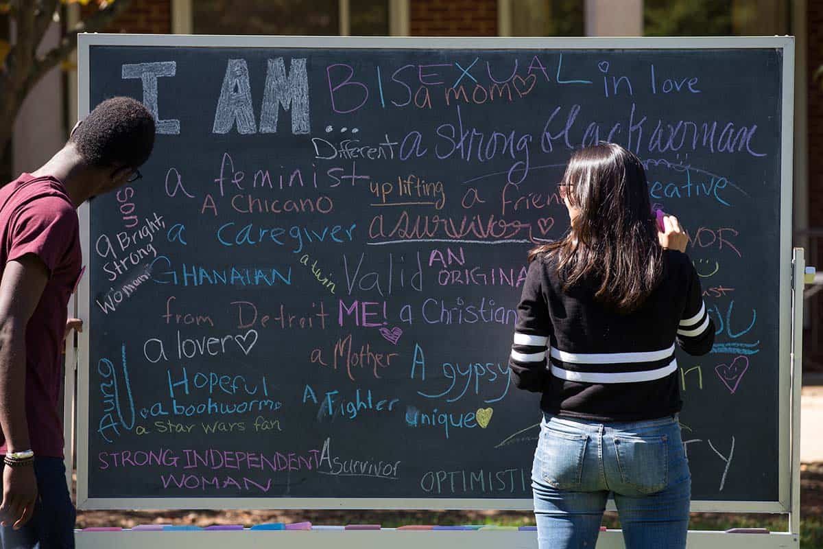 Students share their identities on a diversity chalkboard.