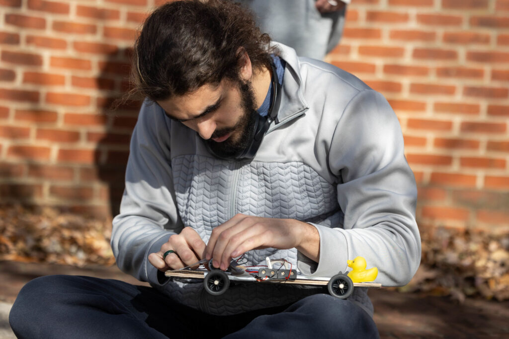 A Randolph College engineering student tests makes adjustments to his solar powered car.