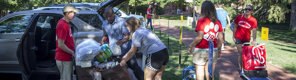 Students help new students and their families unload their cars