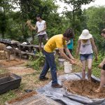 Environmental Studies Professor Karin Warren and Sara Woodward '16 mix up a batch of cob as Sustainability Coordinator Ludo Lemaitre (center) adds more straw at the site where a tiny house could be built.