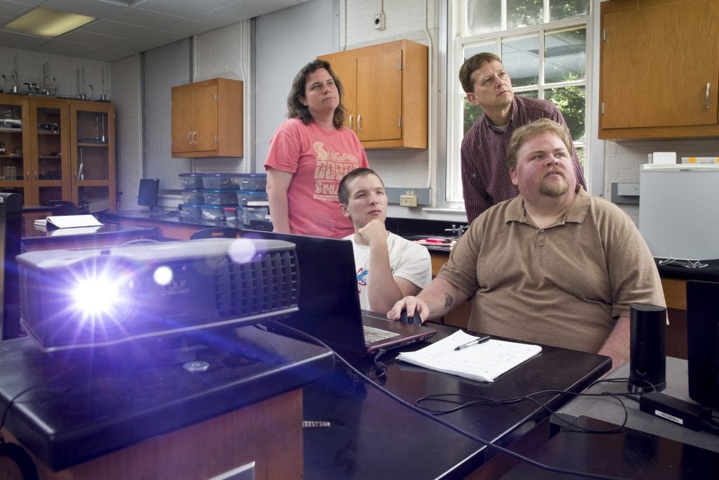 Zach Vernon ’18 (left) and Russ Burt ’16 analyze graphs of car accident statistics with physics professors Peter Sheldon and Sarah Sojka.