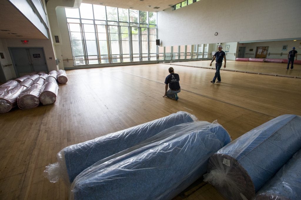 Workers prepare to install the new padded vinyl floor in the dance studio at Randolph College.