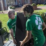 President Brad Bateman and sustainability coordinator Ludovic Lemaitre carry a new student's refrigerator in to her residence hall.
