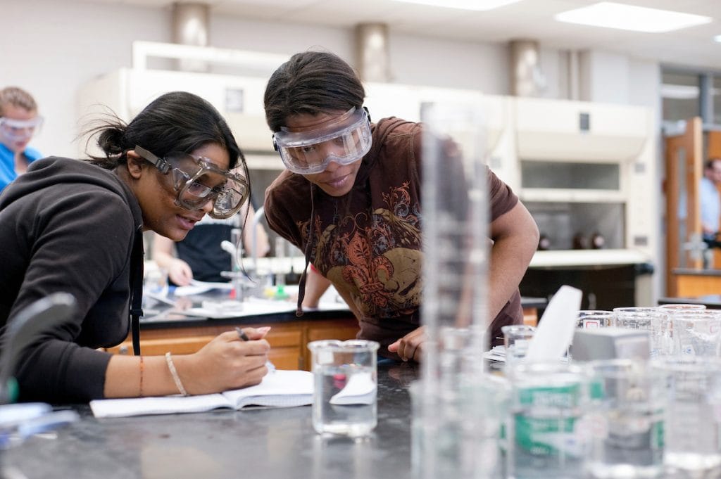 Photo of students looking at a Chemistry experiment in class. Photo of students looking at a Chemistry experiment in class.