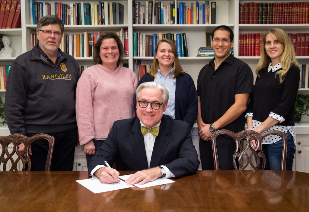 President Bradley W. Bateman signs the President's Resilience Commitment organized by Second Nature. Standing are (from left) Rick Barnes, professor of psychology and environmental studies and the Mary Sabel Girard Chair in Psychology; Sarah Sojka, professor of physics and environmental studies; Sara Woodward '16, sustainability coordinator; Michael Maningas, assistant dean of students; and Karin Warren, Herzog Family Chair of Environmental Studies.