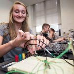 A physics student configures a device that tracks sound levels as part of a Summer Research project.