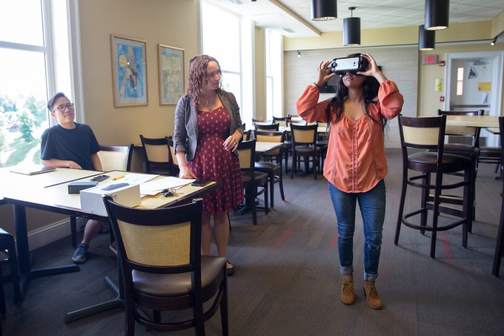 Dung Nguyen '18 (left) and psychology professor Blair Gross watch as Avisha Shah '18 uses the Oculus virtual reality headset.