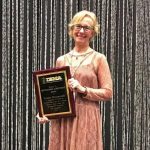 Louisa Branscomb '71 holding her 2017 Distinguished Achievement Award from the International Bluegrass Music Association.