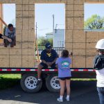 Students hang out in front of the siding for the tiny house.
