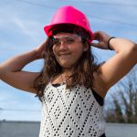 A female student adjusts her pink construction hat on her head.