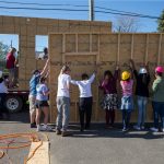 The team of students lifts one of the walls for the tiny house.