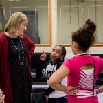 A middle schooler cracks a joke and points her finger at a Randolph student.