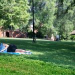 Student laying on the grass, studying on front campus