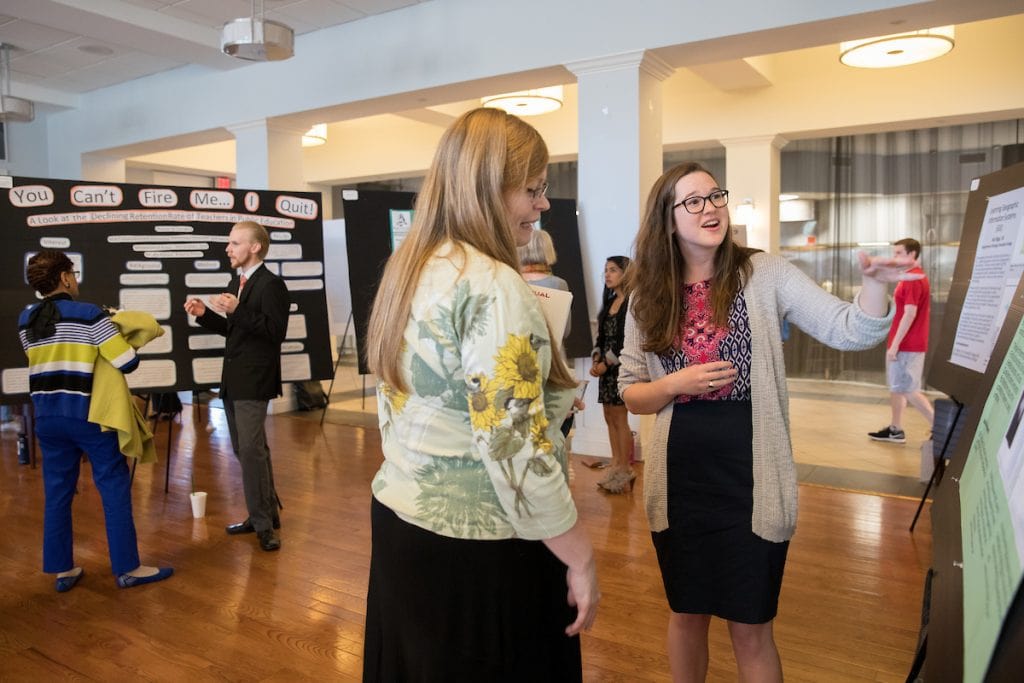 Students explain their work at the poster presentation in the Hampson Commons